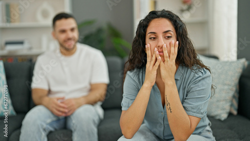 Man and woman couple sitting on sofa arguing stressed at home