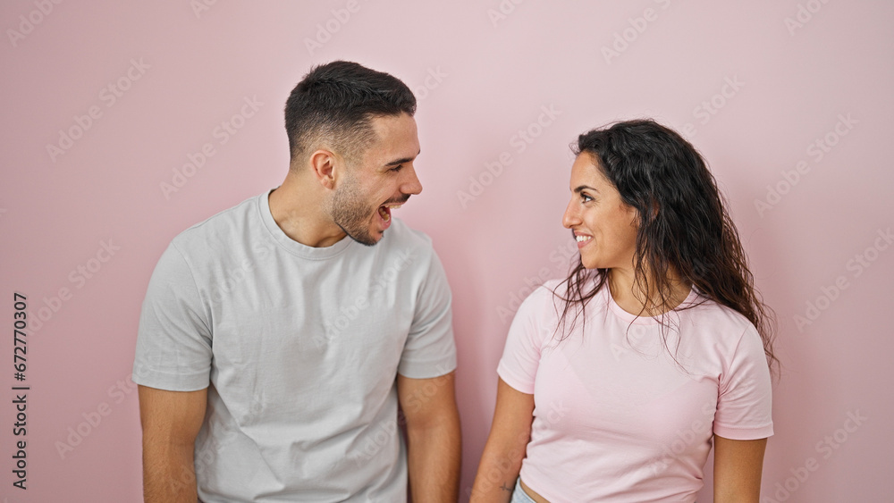 Man and woman couple standing together looking each other over isolated pink background Man and woman couple standing together looking each other over isolated pink background