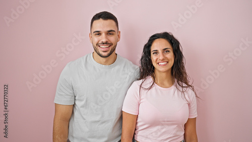 Man and woman couple smiling confident standing together over isolated pink background