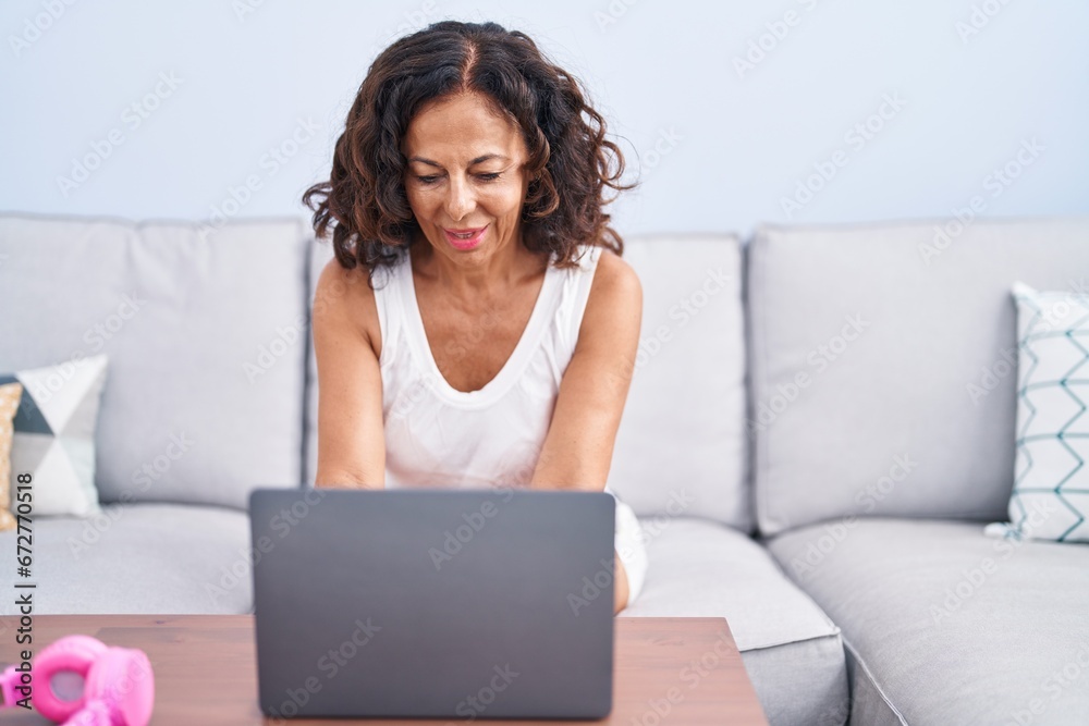 Middle age woman using laptop sitting on sofa at home Middle age woman using laptop sitting on sofa at home