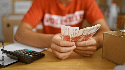Committed young hispanic teen volunteer enthusiastically counting icelandic krona banknotes for a noble cause at a buzzing charity center
