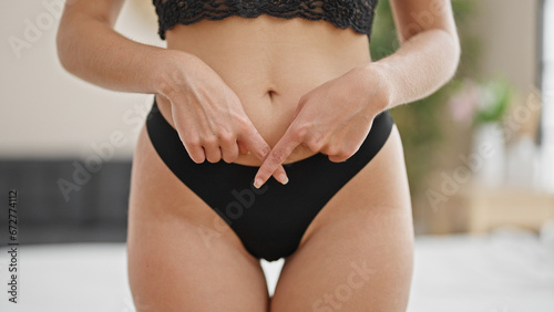 Young blonde woman wearing lingerie doing consent gesture crossing fingers at bedroom photo