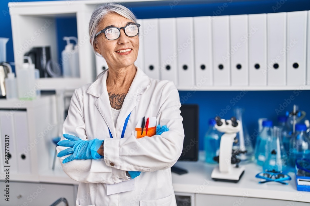 Middle age grey-haired woman scientist smiling confident standing with arms crossed gesture at laboratory