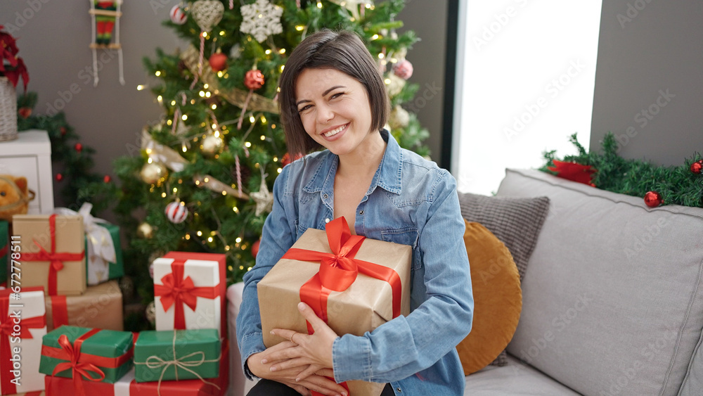 Young caucasian woman holding christmas gift sitting on the sofa at home Young caucasian woman holding christmas gift sitting on the sofa at home
