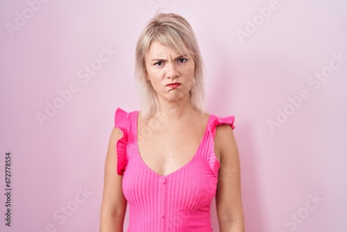 Young caucasian woman standing over pink background skeptic and nervous  frowning upset because of problem. negative person.