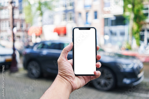 Man holding smartphone showing white blank screen at car parking