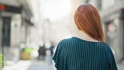 Young redhead woman standing backwards at street
