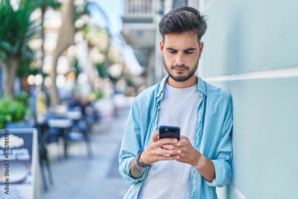 Young hispanic man using smartphone with serious expression at street Young hispanic man using smartphone with serious expression at street