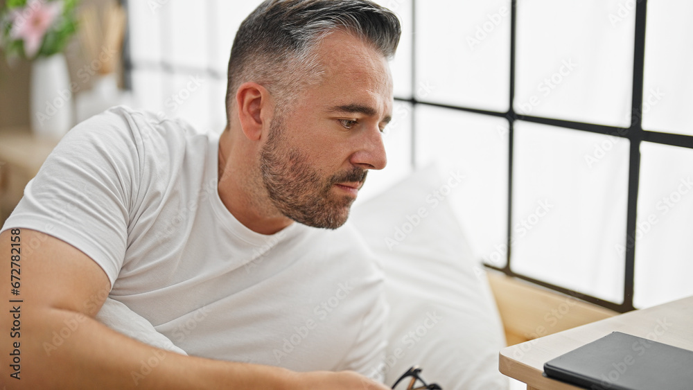 Grey-haired man lying on bed with serious expression at bedroom Grey-haired man lying on bed with serious expression at bedroom