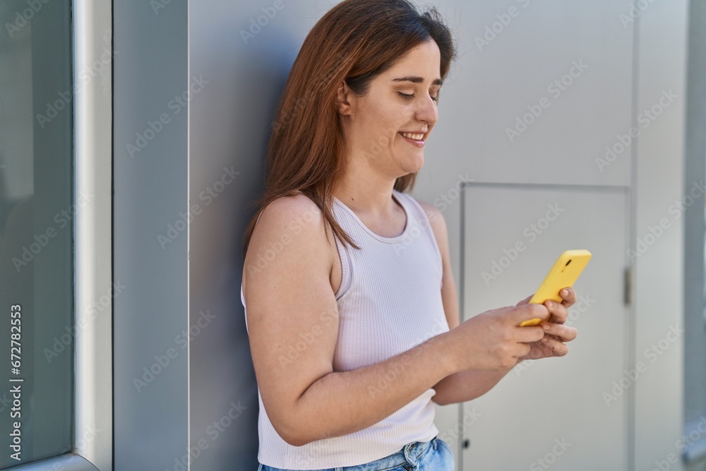 Young woman smiling confident using smartphone at street