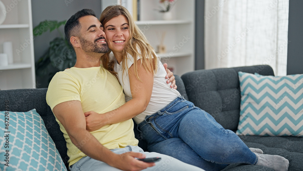 Man and woman couple hugging each other watching television at home