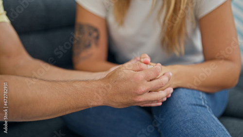 Man and woman couple sitting on sofa with hands together at home
