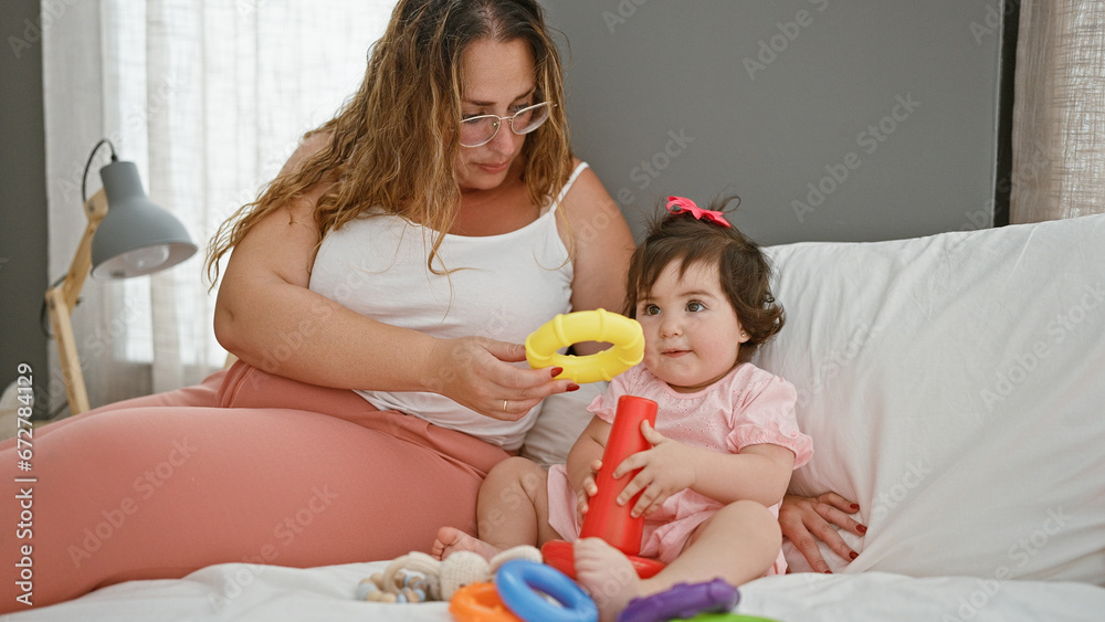 Family morning, mother and daughter relaxing on bed, playing with hoops in homey bedroom Family morning, mother and daughter relaxing on bed, playing with hoops in homey bedroom