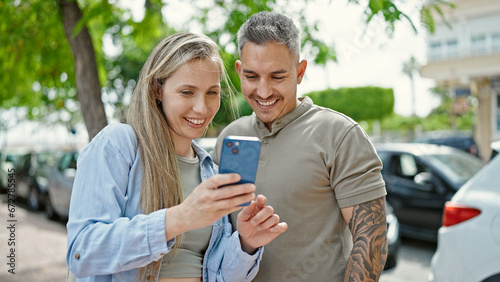 Man and woman couple smiling confident using smartphone at street