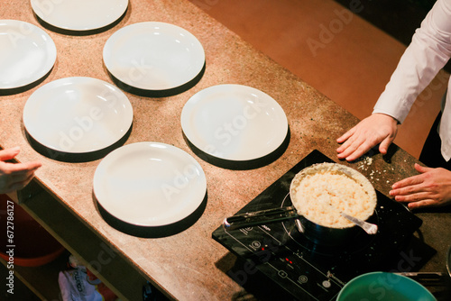 Chef preparing risotto on induction stove for service, ideal for culinary stock images.
