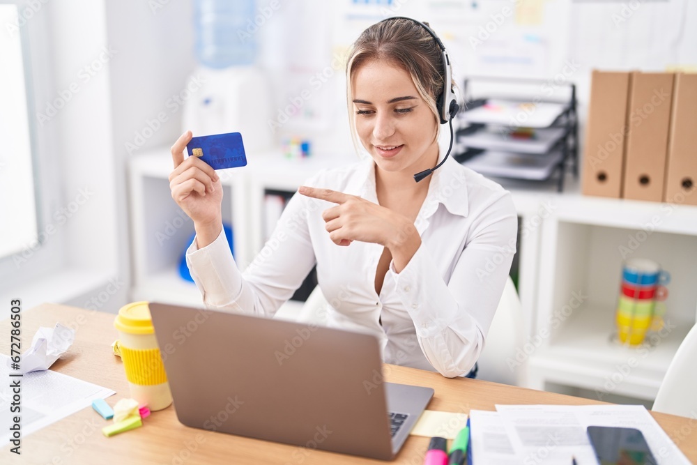 Young blonde woman call center agent holding credit card working at office Young blonde woman call center agent holding credit card working at office