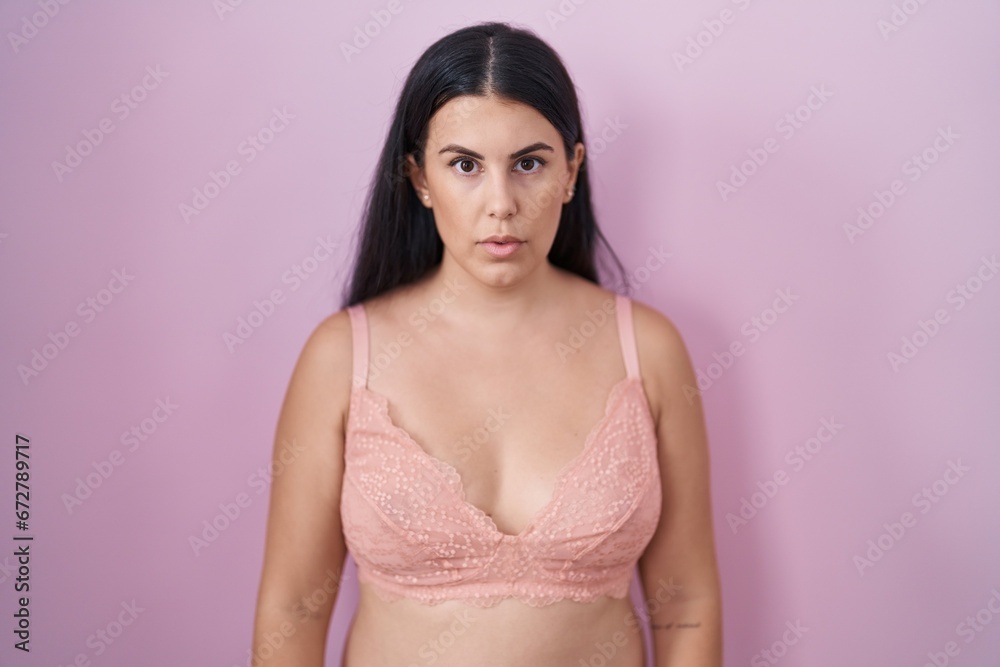 Young hispanic woman wearing pink bra relaxed with serious expression on face. simple and natural looking at the camera. Young hispanic woman wearing pink bra relaxed with serious expression on face. simple and natural looking at the camera.