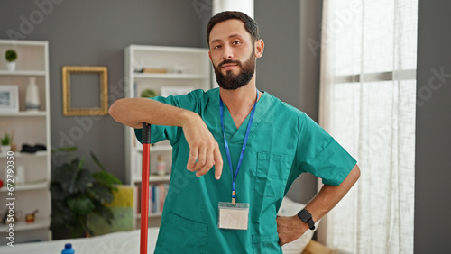 Young hispanic man professional cleaner smiling confident standing at bedroom