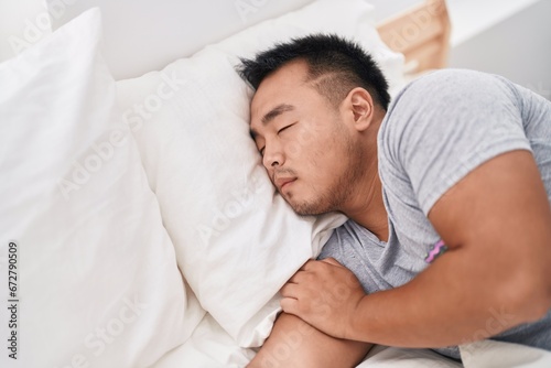 Young chinese man lying on bed sleeping at bedroom
