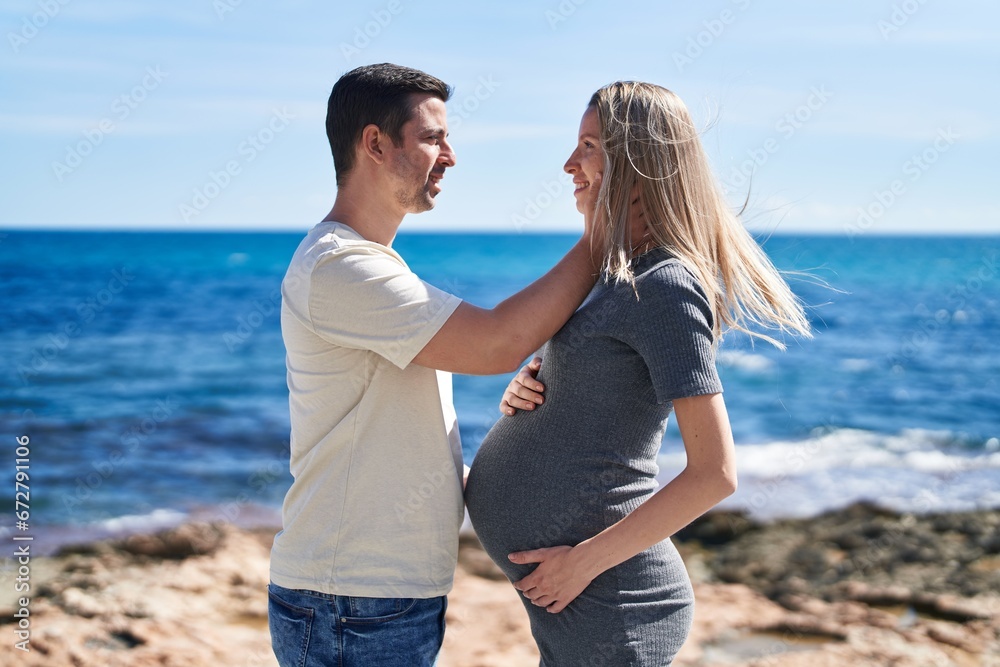 Man and woman couple standing together touching belly at seaside Man and woman couple standing together touching belly at seaside