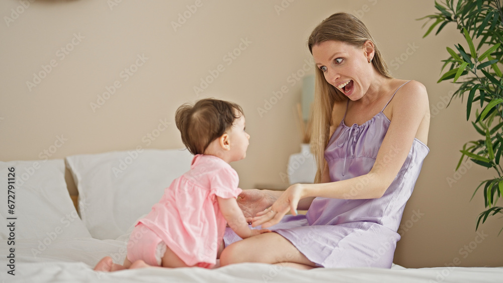 Mother and daughter sitting on bed surprised at bedroom Mother and daughter sitting on bed surprised at bedroom