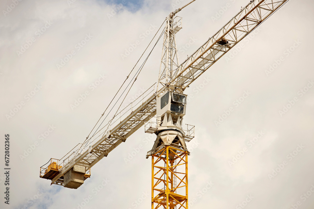 Tower cranes work during the construction of a multi-story building. New apartments for residents and premises for offices. Risky work at height. Lifting heavy building materials. City development