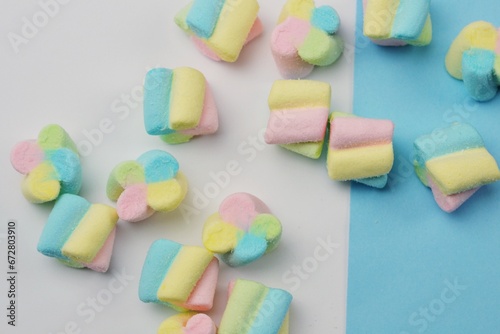 A bunch of multi-colored marshmallows lie on a colored table.
Marshmallows in the form of colored clouds.