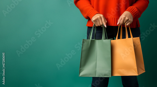 A woman holds shopping bags in her hands on a green background
