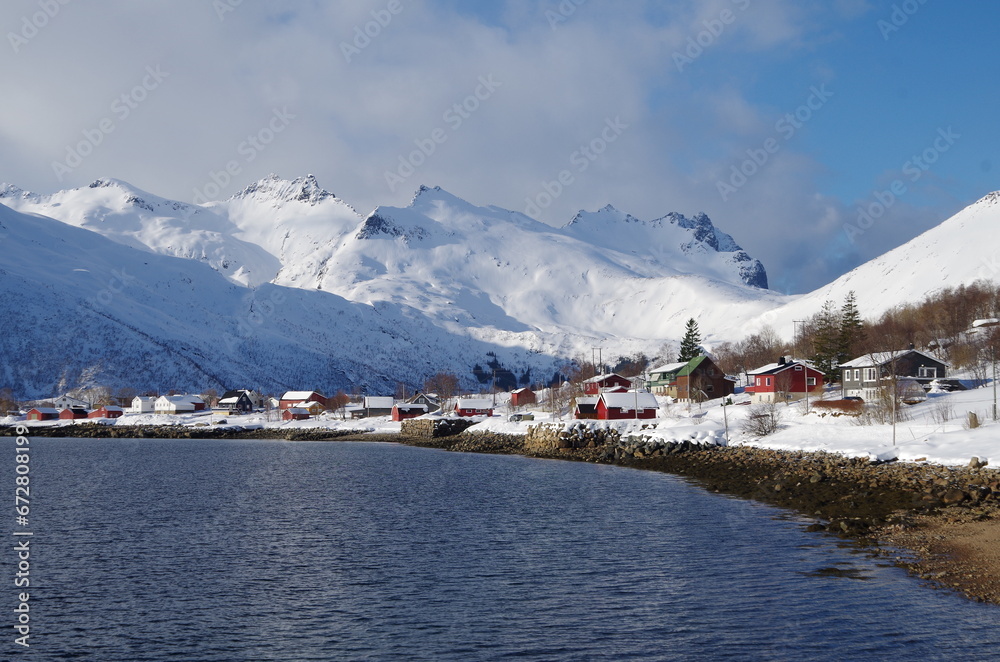 Lofoten Islands in winter time: ski touring, snowy mountains, red houses, fishermen boats and scenic landscapes