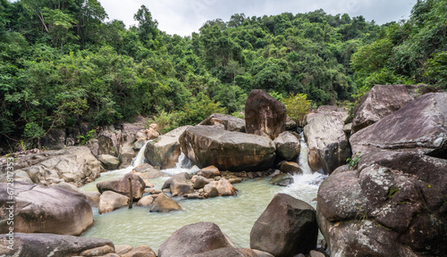 Jungle waterfall with rapid waters and large rocks in Vietnam.