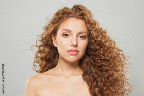 Gorgeous woman with wavy hair and natural makeup. Fashion model with long curly hairstyle and fresh clear skin posing on white background