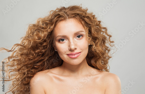 Cute stylish young female model with curly long brown hairstyle on white background. Woman with wavy hair