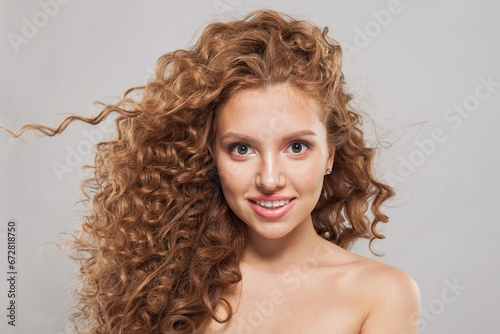 Happy stylish young female model with curly long brown hairstyle on white background. Woman with wavy hair