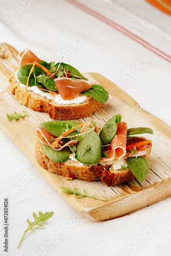 two sandwiches with spinach, jamon and carrots on a wooden board, close-up, top view, white background