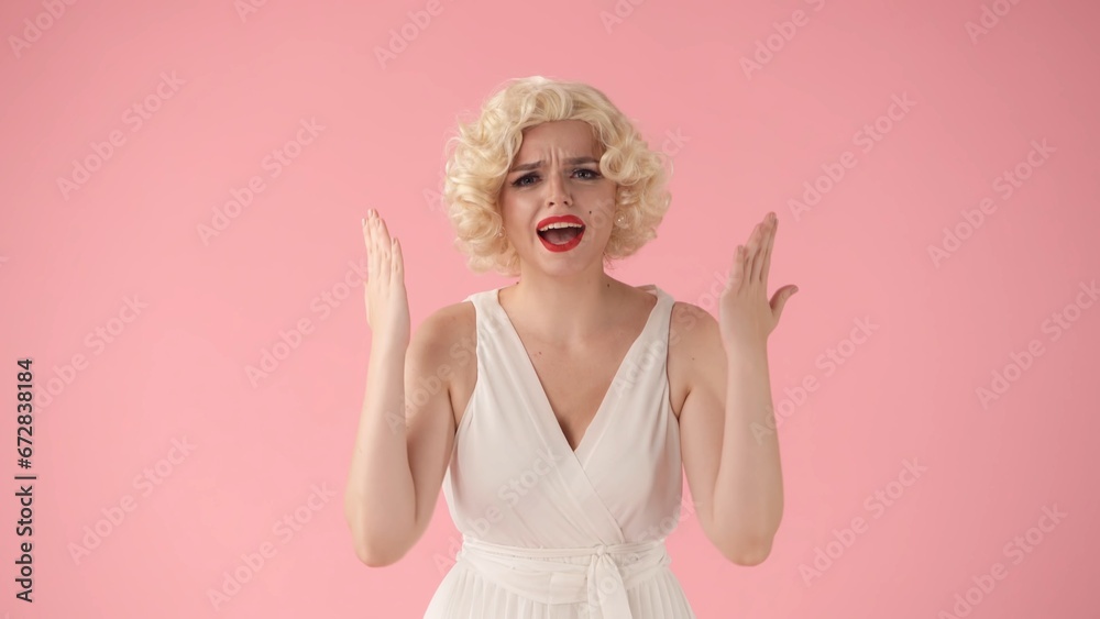 A woman in the image of swearing in a studio against a pink background in close up. A woman in the image of swearing in a studio against a pink background in close up.
