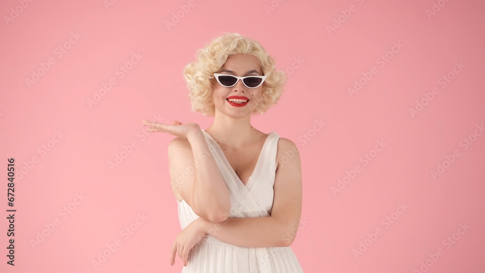 Portrait of a woman in the image of wearing cat eye shape sunglasses in studio on pink background. Portrait of a woman in the image of wearing cat eye shape sunglasses in studio on pink background.