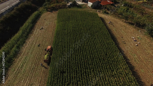 Aerial Photography of a farm tractors harvesting corn from a field, bright sunny day