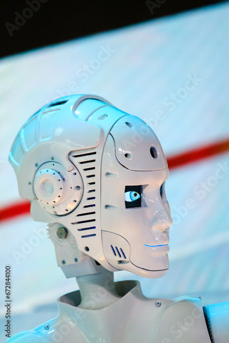 Closeup of white illuminated human robot looking away against blurred background