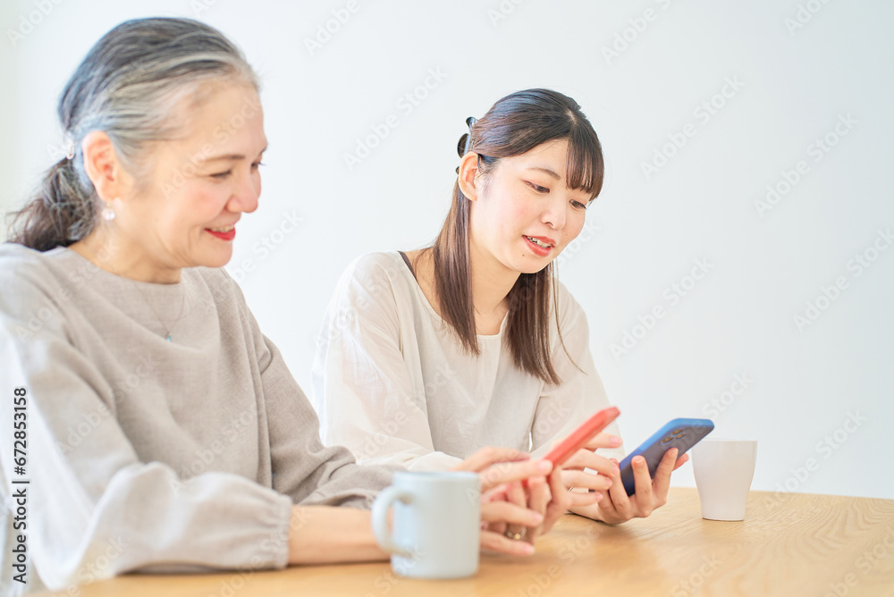 スマートフォンを操作するシニア女性と若い女性 スマートフォンを操作するシニア女性と若い女性