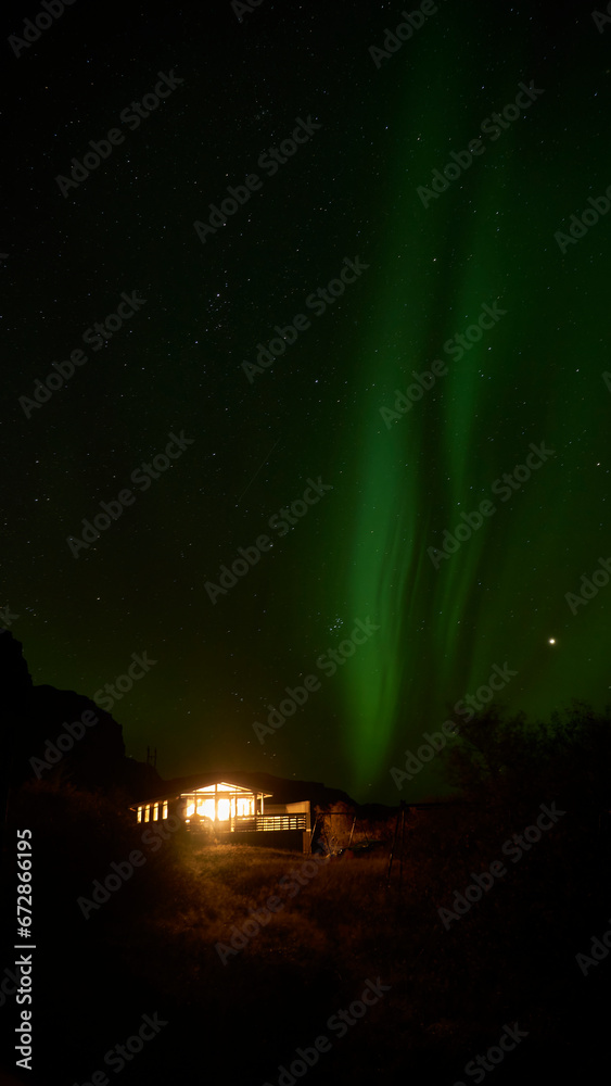 aurora borealis behind icelandic summer house