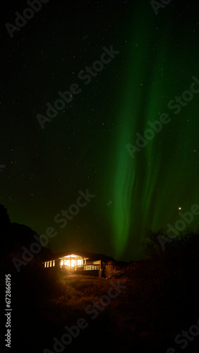 aurora borealis behind icelandic summer house