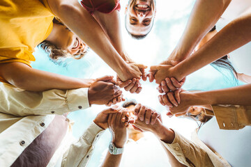 Multi ethnic group of young people holding hands outdoors - Community life style concept with guys and girls hugging together outside - Unity, support and collaboration concept