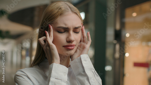 Caucasian woman sick girl in shopping mall close-up portrait stressed unhealthy businesswoman touching head rubbing temples covid19 symptom suffer from migraine pain difficult decision health problem