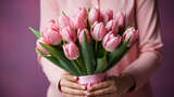 Bouquet of pink tulips in hand. Pink background with copy space. High quality photo.
