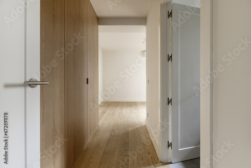Small entrance hallway to a modern designed bedroom with custom-made built-in wardrobe with light oak wooden doors and matching floors