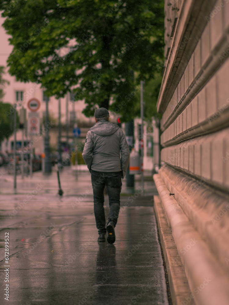 Male walking down a wet sidewalk illuminated by the afternoon sun on a rainy day
