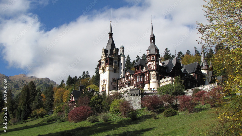 a castle in the countryside near a mountain range with trees and bushes