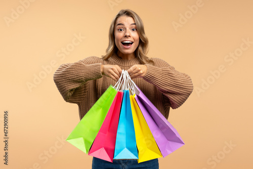 Young beautiful excited woman wearing holding colorful shopping bags looking at camera isolated on  background. Shopping, black Friday, sale, advertisement concept photo
