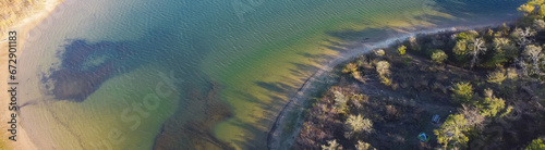 Panorama curved shoreline and remote waterfront primitive camping sites with tents at Isle du Bois Ray Roberts Lake State Park lush green tree forest near Denton, Texas, US aerial view