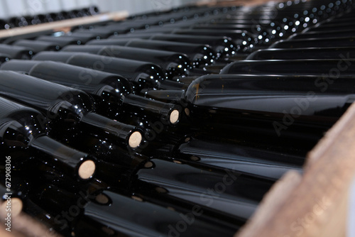 Wine bottles are stacked for storage. Bottles lie in rows. Young wine.Craft winery. Selective focus. Vertical photo.